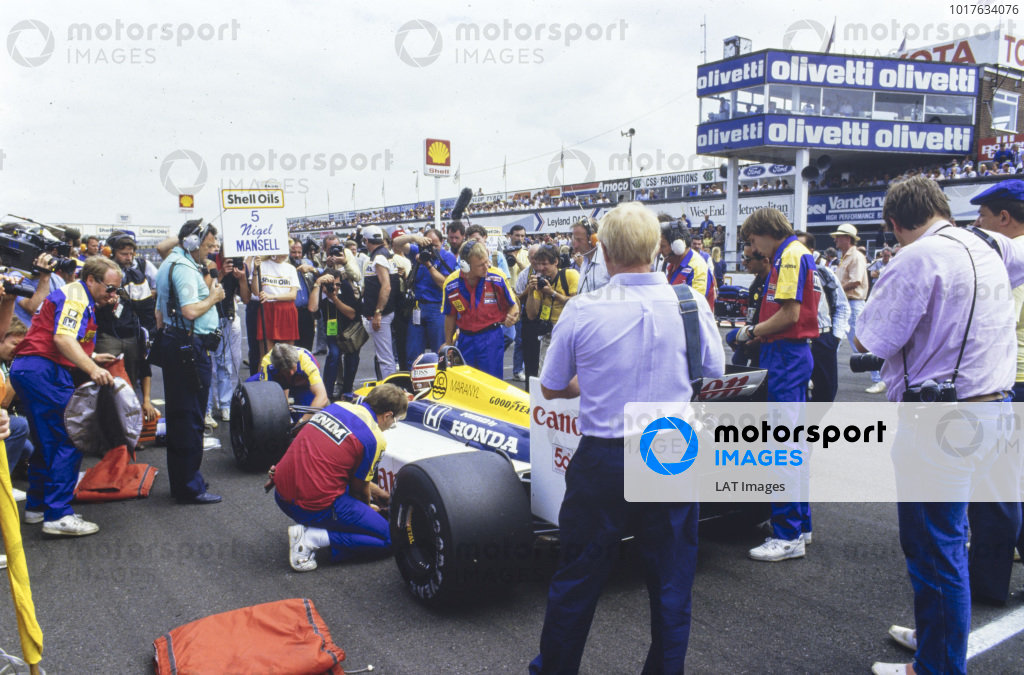 Nigel Mansell, Williams FW11B Honda, on the grid. Barrie Gill stands with microphone in hand. Nigel Mansell, Williams FW11B Honda, on the grid. Barrie Gill stands with microphone in hand.