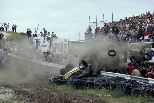 Rene Arnoux, Renault RE30B, crashes into a tyre barrier sending loose tyres flying towards photographers, after a wheel (far left of frame) came off his car.