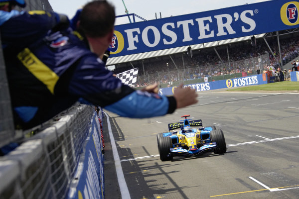 Fernando Alonso, Renault R26 takes he chequered flag for victory as his team celebrate on the pitwall.